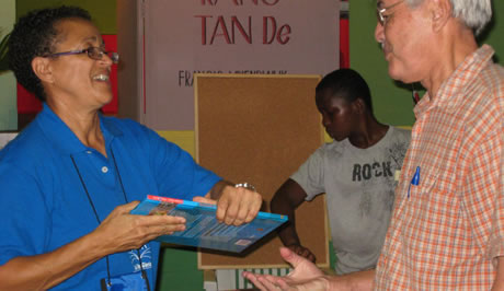 Karin Blufpand overhandigt een exemplaar van <em>Op bezoek in Suriname</em>